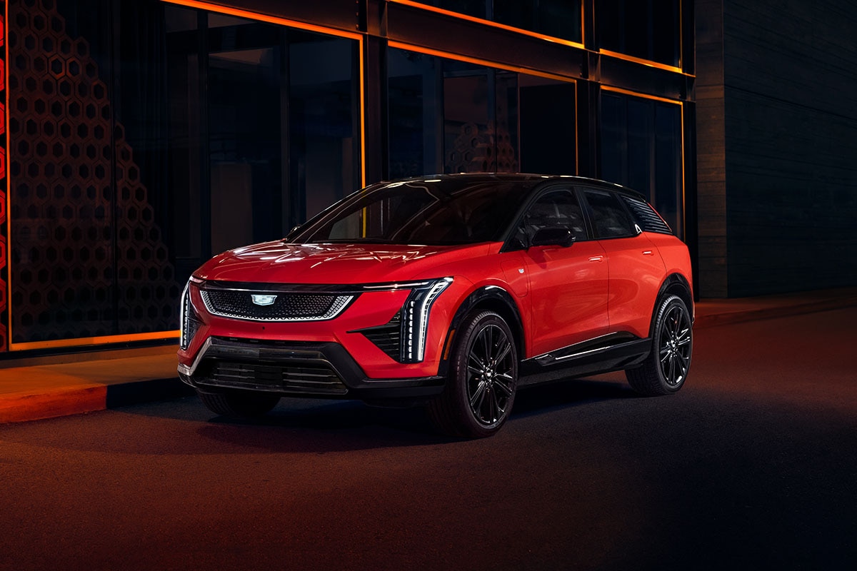 Cadillac OPTIQ 2027 en color Radiant Red frente a una fachada iluminada