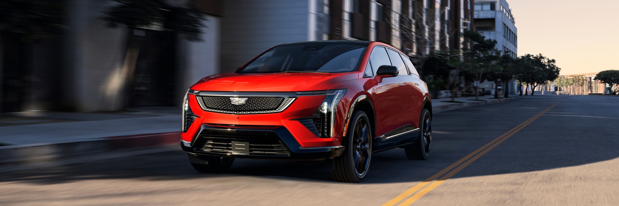 Cadillac OPTIQ 2027 en color Radiant Red circulando por una avenida